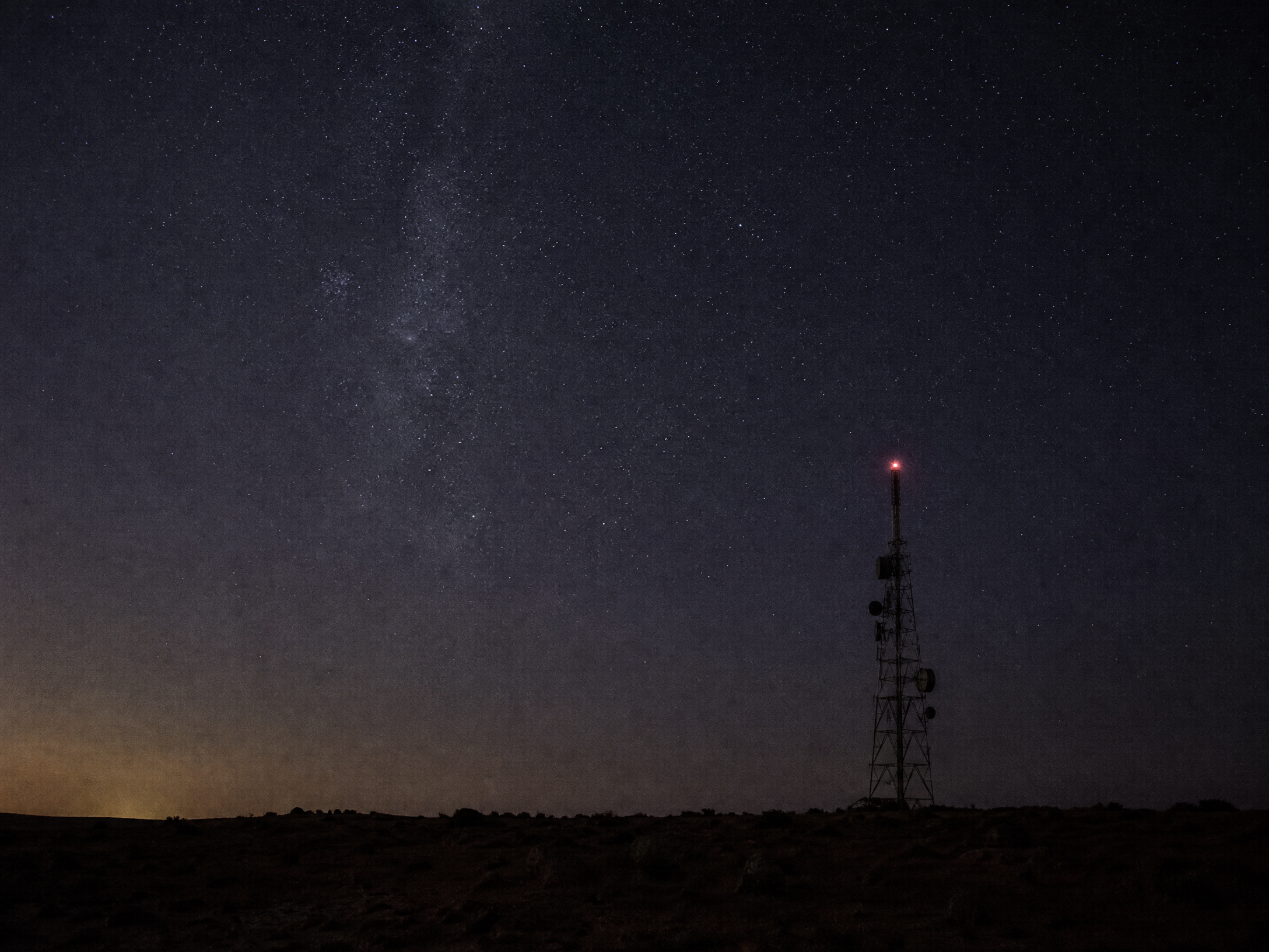 Night desert landscape and communications mast