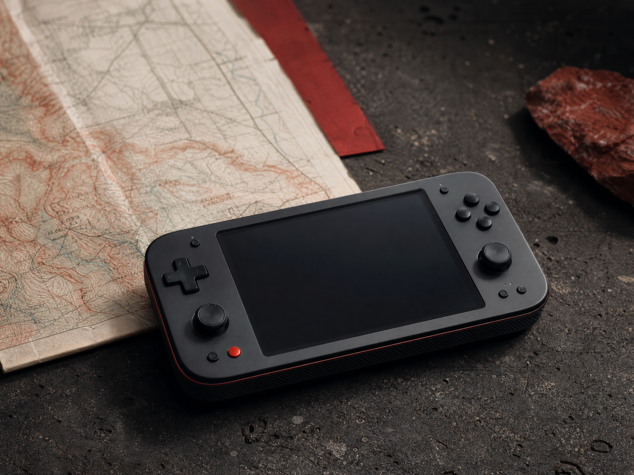 A game device on a charcoal workbench beside a map
